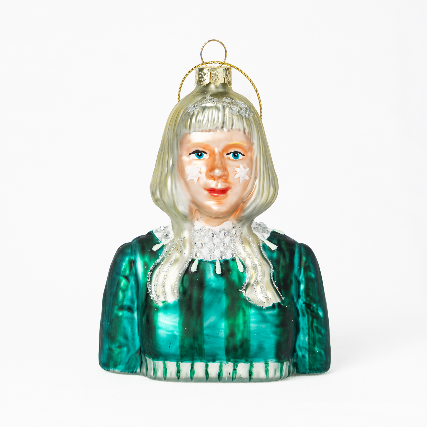 Aurora Aksnes julekule, blondt hår, stjerner på kinnene, grønn kjole med glitterdetaljer og smykker.
Aurora Aksnes Christmas ornanment, blonde hair, stars on her cheeks, green dress with glitter details and jewelry.