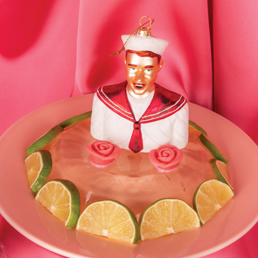 Fagott julekule 2025 fra HEIM Studio – håndmalt glassfigur i hvit og magenta matrosdress med rødt hår og bart, laget i samarbeid med Oslo Fagottkor.