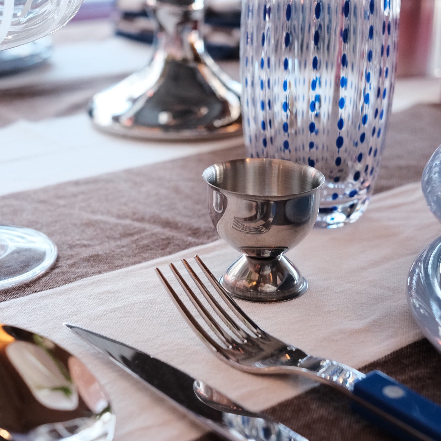 Eggeglass i stål - by Heim Design med rund form og stabil fot på bord dekket til frokost med bestikk og glass