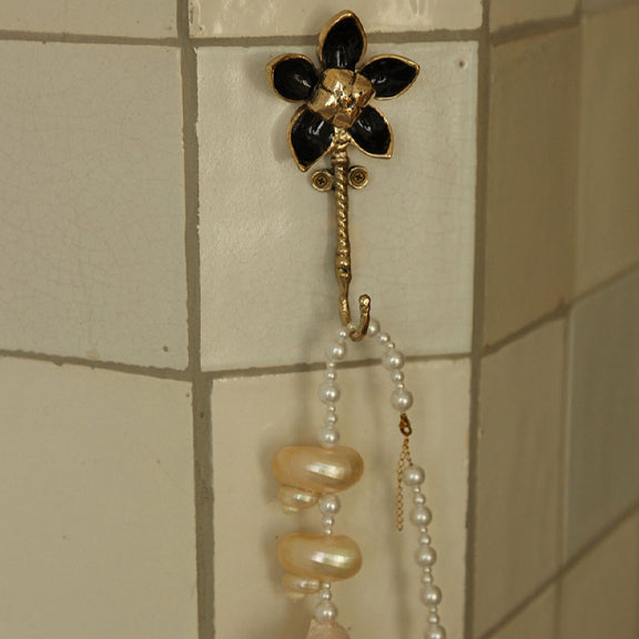 Liv Blomster Krok - By Doing Goods med resirkulert messing i blomstermotiv på flisvegg