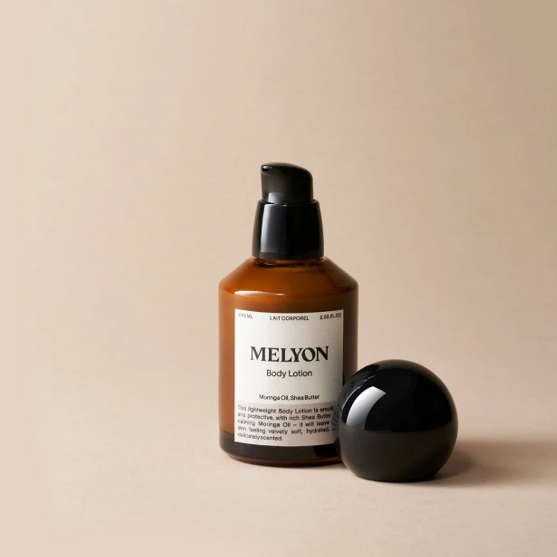 Brun flaske med pumpe og svart rund kork for Body Lotion Shea Butter 60 ML - By Melyon på beige bakgrunn