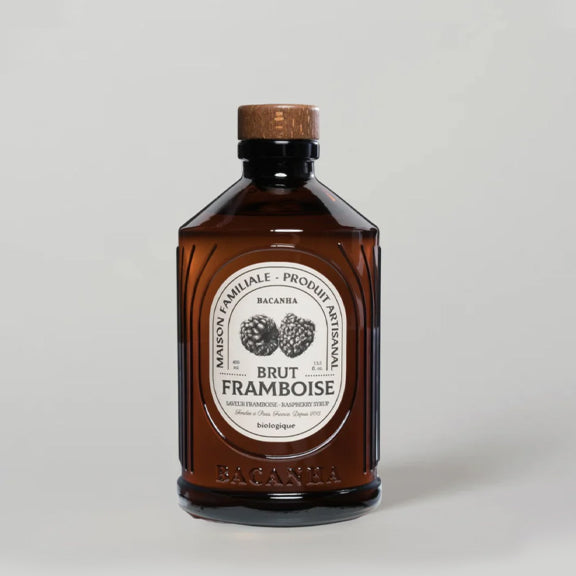 Raspberry Organic Syrup - By Bacanha i mørkt glass med elegant hvit etikett og trelokk på nøytral bakgrunn