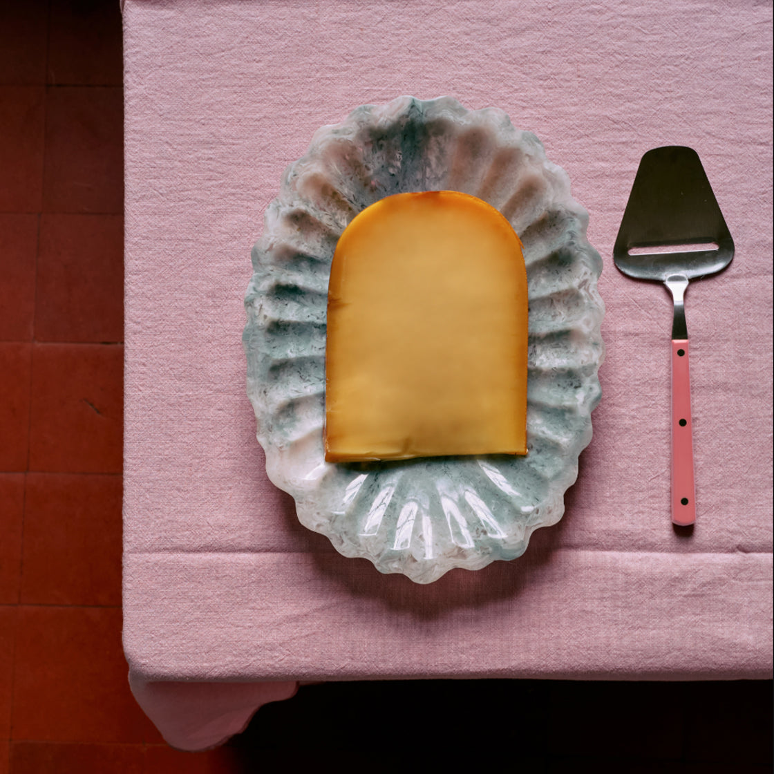 Ostehøvel Rosa - By HK Living med bringebærrosa håndtak ved keramisk fat med ost på rosa stoff