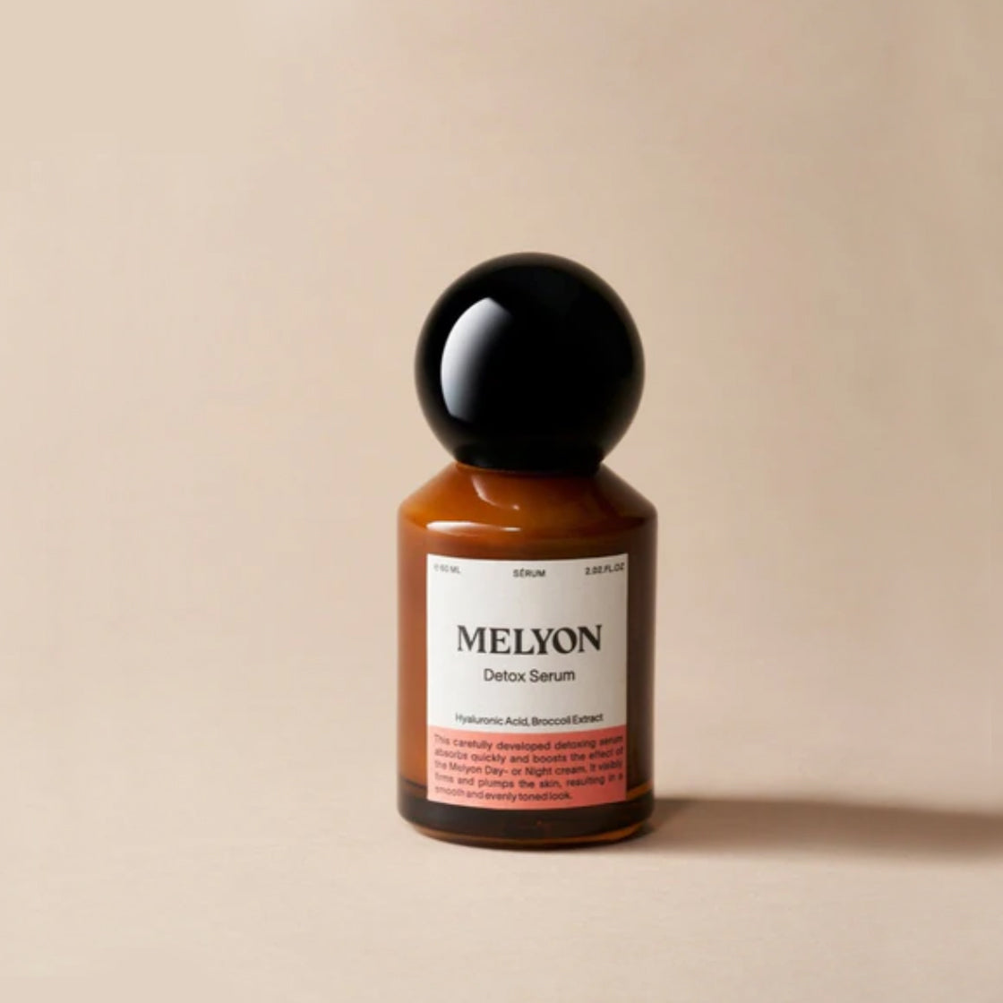 Brunt glassflaske med svart kuleformet lokk og etikett for Detox Serum 60 ML - By Melyon på enkel bakgrunn