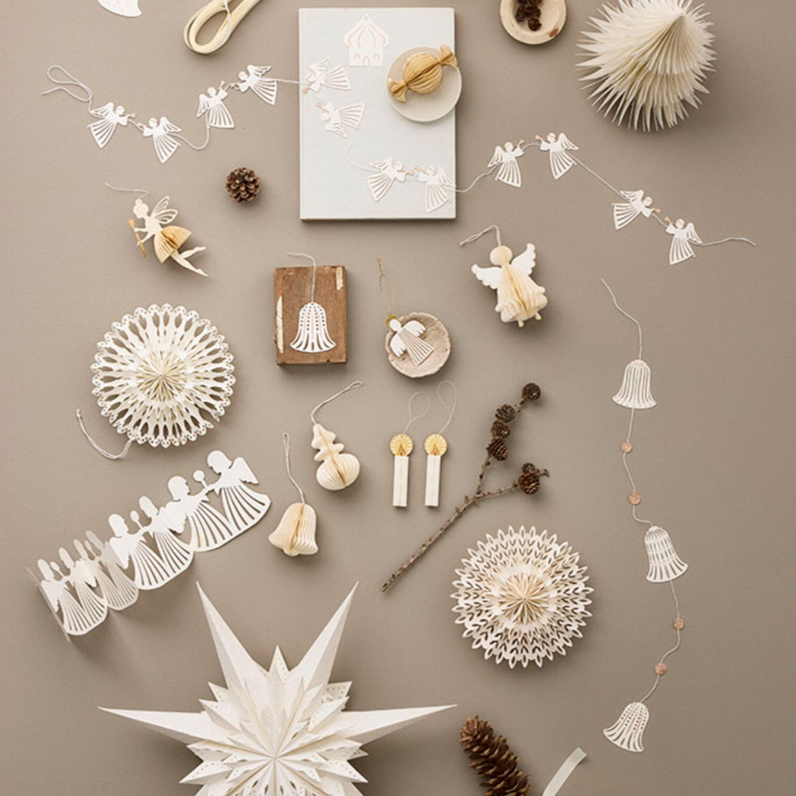 Girlander Engler - By Bungalow med intrikate, laserskårne engler i papir og gullglitter på beige bakgrunn.