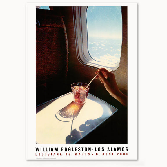 Jubileumsplakat av William Eggleston - Lousianna print. Printet viser et retro bilde av noen som rører i en cocktail i et fly, langt oppe i luften.