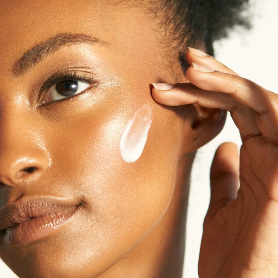 Nærbilde av kvinne som påfører Nattkrem Vitamin-A 60 ML - By Melyon med krem på kinnet i naturlig lys