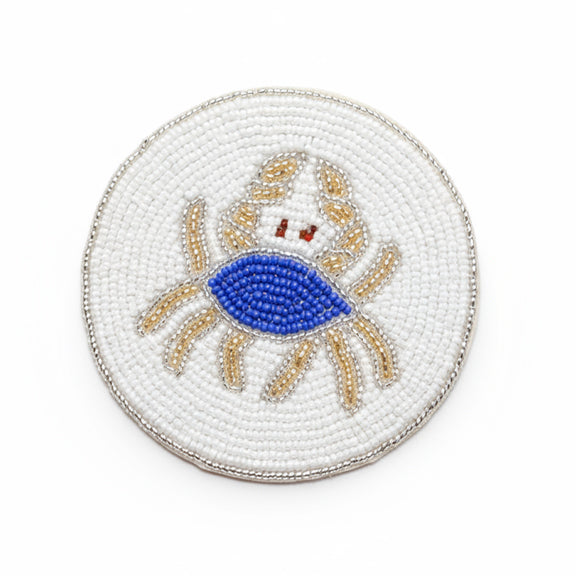 Drikkebrikker Krabbe Blå/Hvit - By HEIM Studio med rund perlebrodert krabbe i blått, hvitt og beige på hvit bakgrunn