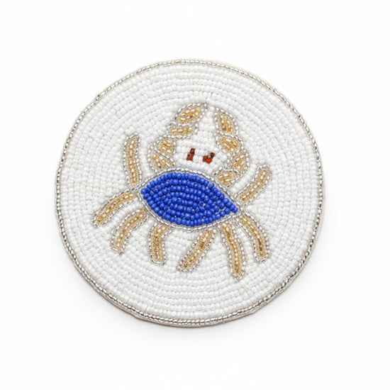 Drikkebrikker Krabbe Blå/Hvit - By HEIM Studio med rund perlebrodert krabbe i blått, hvitt og beige på hvit bakgrunn