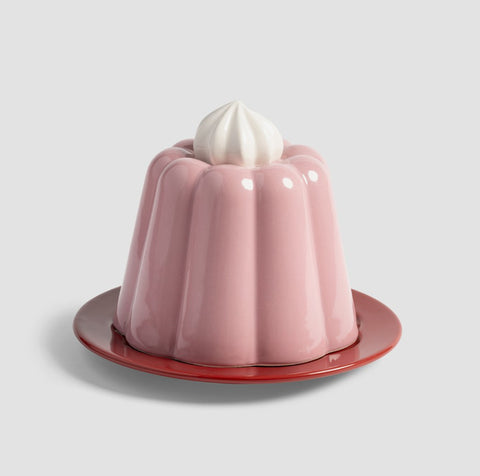 Osteklokke Pudding Rosa - By &Klevering med rosa puddingformet lokk og kreminspirert håndtak på rød tallerken